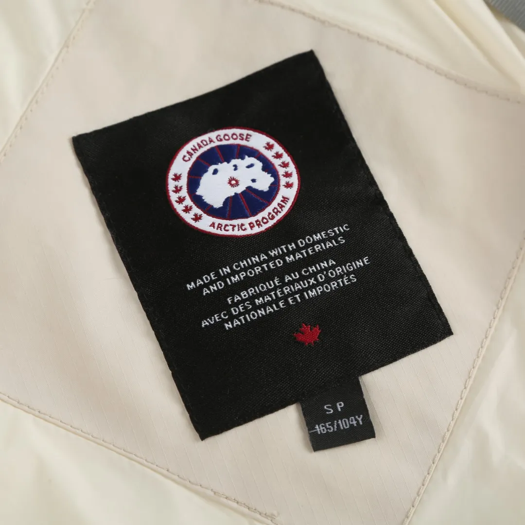 P1060 Canada Goose hooded down jacket fabric selection; nylon fabric is known for its high strength, excellent wear and tear resistance, and excellent durability. At the same time, it is light in texture, easy to move, and has excellent water-repellent function, which can effectively deal with light rain and humidity. Technology: Double-needle quilting technology is used. Double-needle quilting technology is a sophisticated sewing technology. Its core feature is to use two needles to quilt at the same time to form two parallel stitches. This design not only makes the quilting lines visually more three-dimensional, regular and refined, but more importantly, it greatly enhances the firmness of the sewing. The double lines in parallel form a more stable structure, which can effectively lock the internal filling and significantly prevent it from shifting, accumulating or velveting during wearing or washing, thereby ensuring that the thermal insulation layer is evenly distributed without cold spots, and comprehensively improves the durability and thermal efficiency of the product.    High-quality filling: It is filled with 90% selected white duck down, weighing 170g, ensuring fluffy rebound, lightness and warmth.  Accessories: one-to-one customized three-standard, one-to-one customized zipper, one-to-one customized hardware